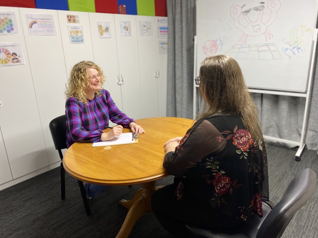 Sarah working with an adult client at a table