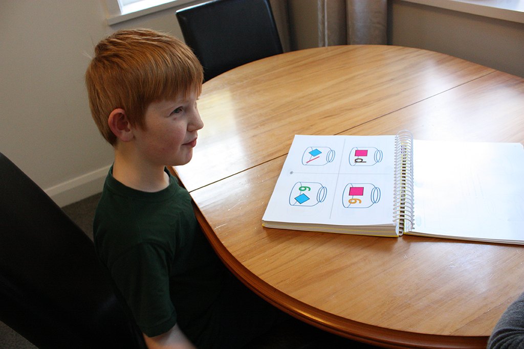 A boy looking at a book of picture symbols on a table