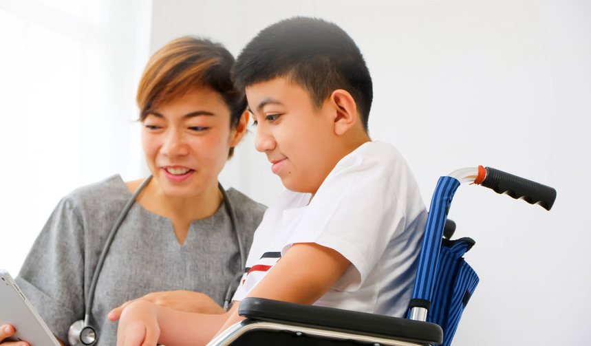 A therapist working through a communication board with a young man in a wheelchair