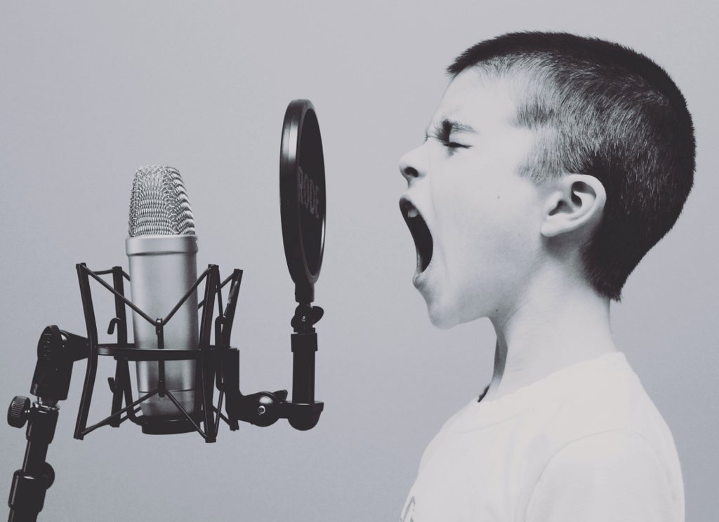 A boy projecting his voice into a studio microphone